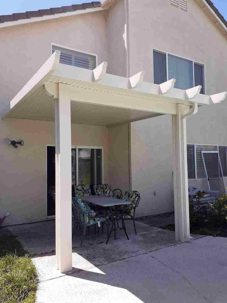 A patio in Sacramento, CA, featuring a pergola and a table set underneath for outdoor dining